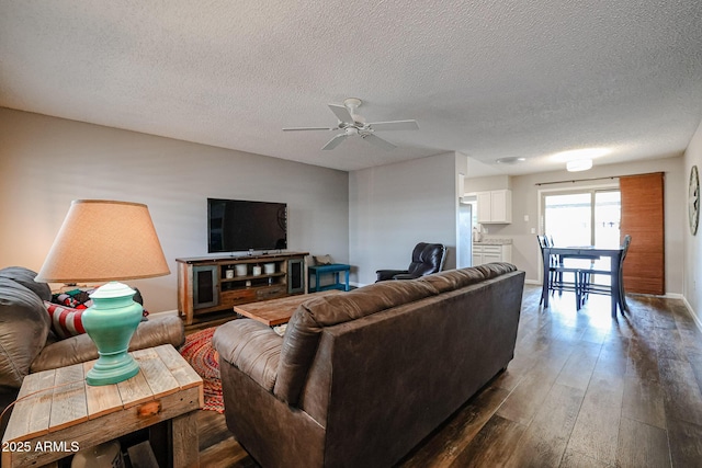 living room with a textured ceiling, dark hardwood / wood-style flooring, and ceiling fan