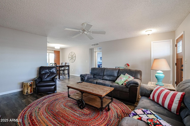 living room featuring dark hardwood / wood-style floors, ceiling fan, and a textured ceiling