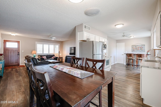 dining area featuring ceiling fan, dark hardwood / wood-style floors, and a textured ceiling