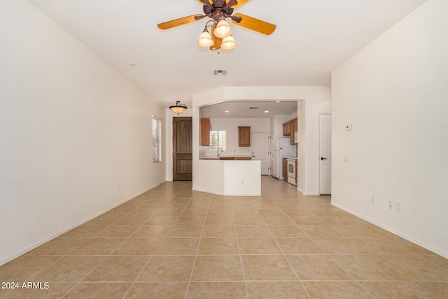 unfurnished living room featuring sink, light tile patterned floors, and ceiling fan