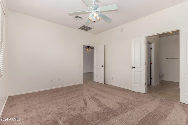 unfurnished bedroom with ceiling fan, ensuite bath, and carpet flooring