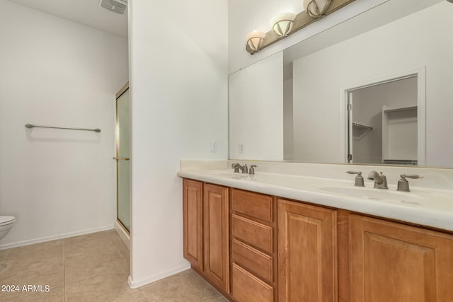 bathroom featuring vanity, tile patterned flooring, toilet, and a shower with door