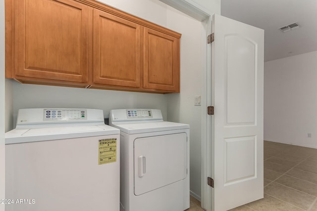 clothes washing area featuring cabinets, light tile patterned floors, and washer and dryer