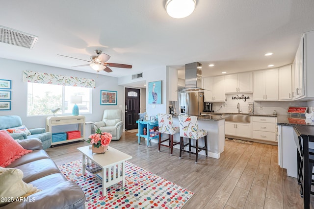 living room with ceiling fan, sink, and light hardwood / wood-style flooring