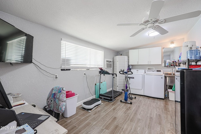 workout area with vaulted ceiling, washing machine and clothes dryer, ceiling fan, light hardwood / wood-style floors, and a textured ceiling