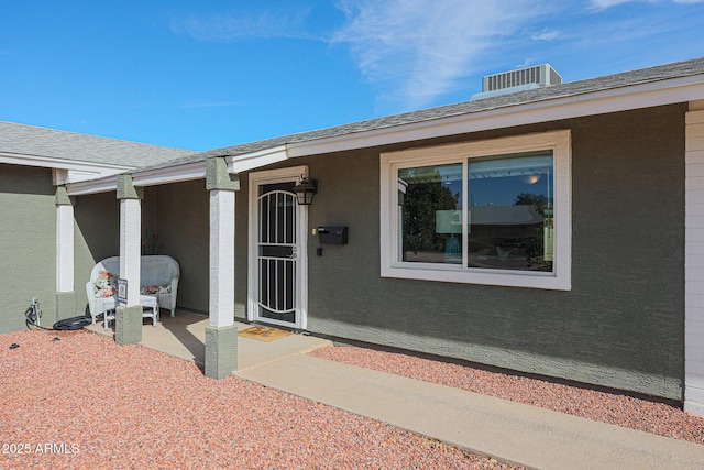 view of exterior entry with central AC unit and a patio area