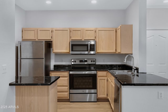 kitchen with light wood finished floors, light brown cabinetry, appliances with stainless steel finishes, and a sink