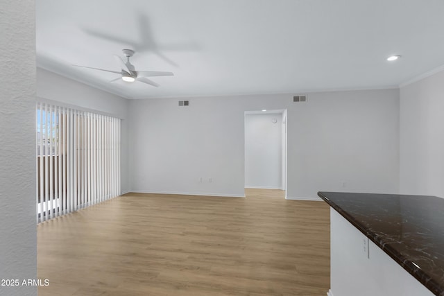 unfurnished living room with crown molding, visible vents, ceiling fan, and light wood finished floors