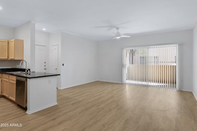 kitchen with stainless steel dishwasher, dark countertops, a sink, and light wood-style floors