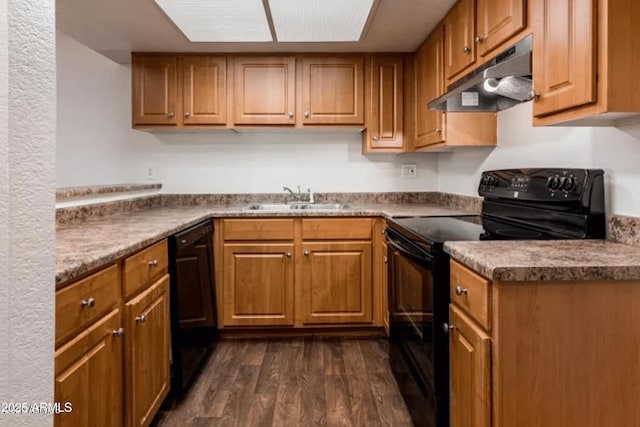 kitchen featuring under cabinet range hood, brown cabinets, dark wood-style floors, black appliances, and a sink