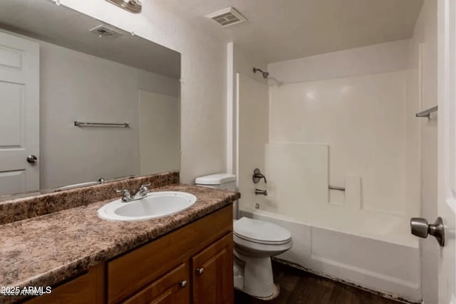 full bath featuring vanity, wood finished floors, visible vents, shower / bath combination, and toilet