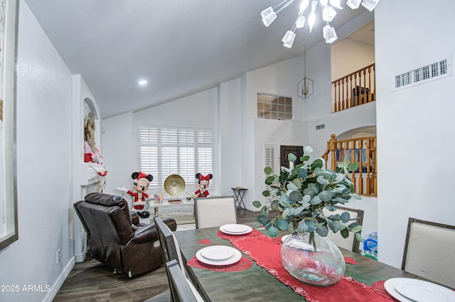 dining space with high vaulted ceiling, an inviting chandelier, and hardwood / wood-style flooring