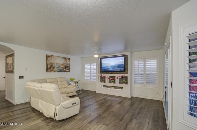 living room featuring ceiling fan, a textured ceiling, and dark hardwood / wood-style flooring