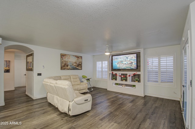 living room featuring ceiling fan, a textured ceiling, and dark hardwood / wood-style floors