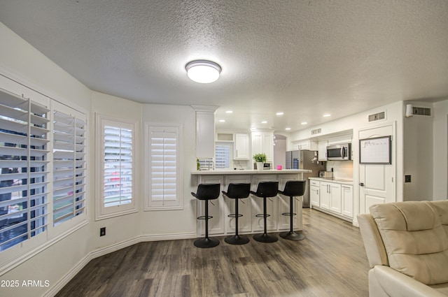 kitchen with a kitchen bar, appliances with stainless steel finishes, decorative backsplash, light wood-type flooring, and white cabinets