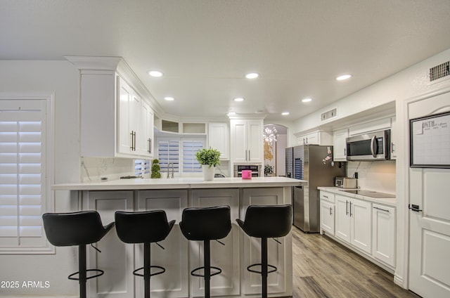 kitchen featuring white cabinetry, stainless steel appliances, tasteful backsplash, sink, and a breakfast bar area