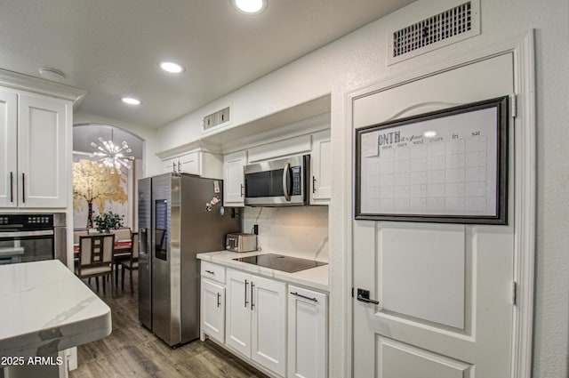 kitchen featuring light stone countertops, appliances with stainless steel finishes, white cabinetry, dark hardwood / wood-style flooring, and decorative backsplash