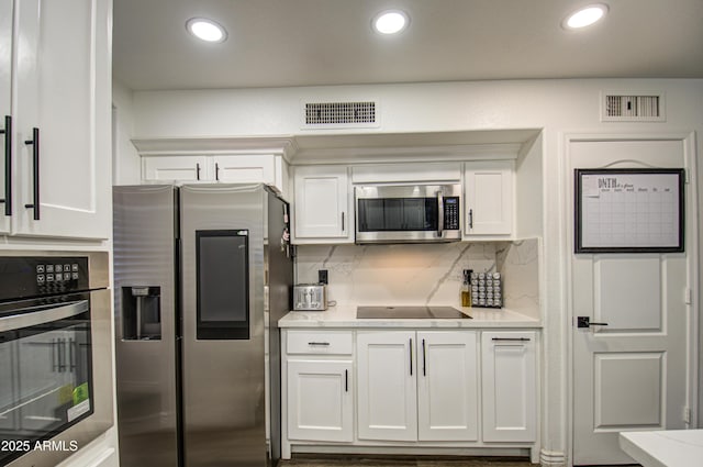 kitchen featuring white cabinets, decorative backsplash, and stainless steel appliances