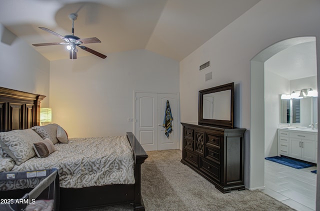 carpeted bedroom with ceiling fan, lofted ceiling, and ensuite bath