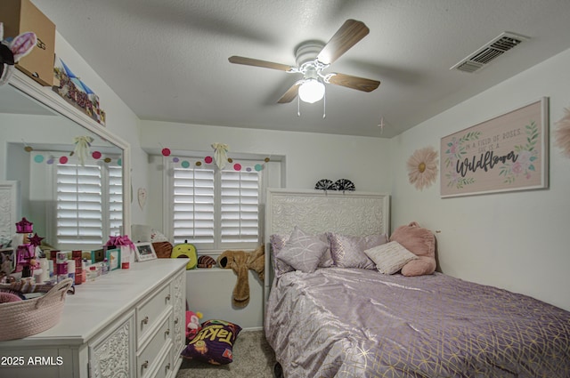 bedroom with a textured ceiling, ceiling fan, and carpet