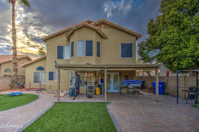 back house at dusk with a lawn and a patio