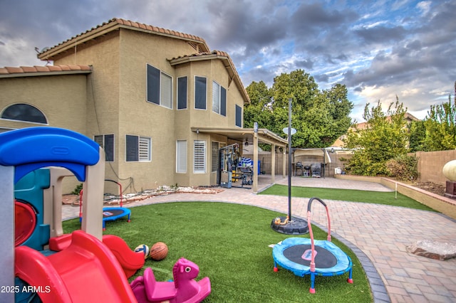 back of house featuring a lawn, a patio area, and a playground