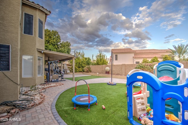 view of jungle gym with ceiling fan, a patio area, and a lawn