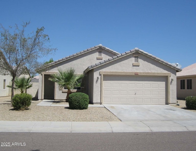 view of front facade with a garage, concrete driveway, a tiled roof, and stucco siding