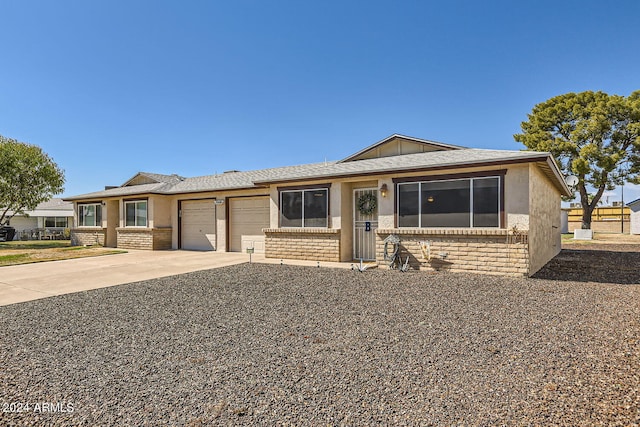 ranch-style house with a garage, brick siding, driveway, and stucco siding