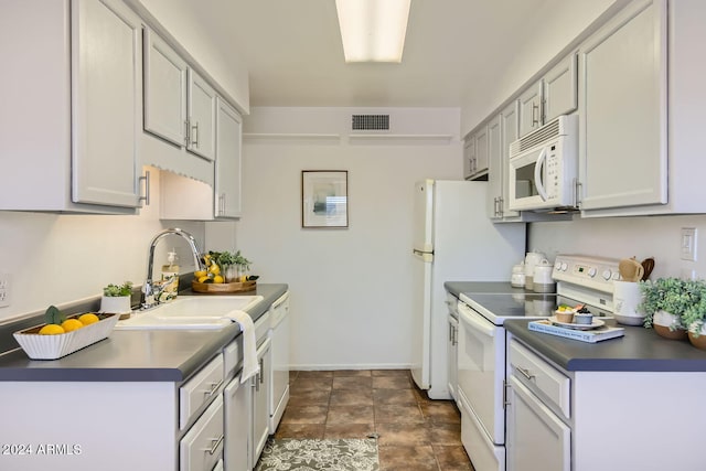 kitchen featuring white appliances, baseboards, visible vents, dark countertops, and a sink