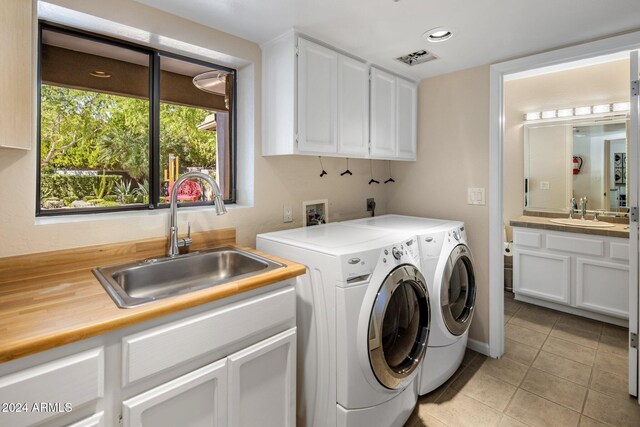 laundry area featuring sink, independent washer and dryer, light tile patterned floors, and cabinets