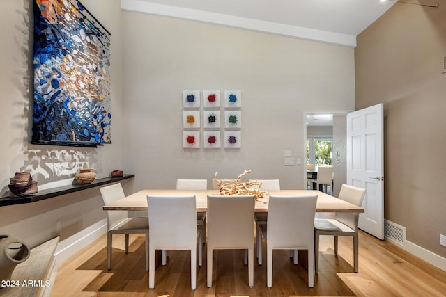 dining room with high vaulted ceiling and light wood-type flooring