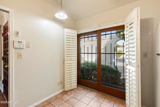 doorway with vaulted ceiling, light tile patterned floors, and baseboards