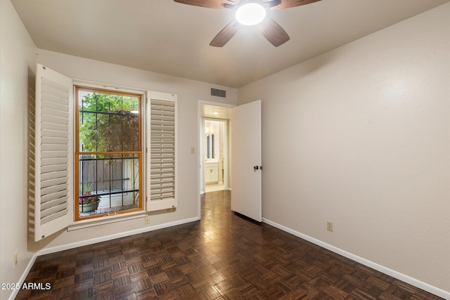 empty room featuring a ceiling fan, visible vents, and baseboards