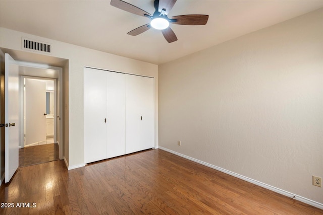 unfurnished bedroom featuring ceiling fan, dark hardwood / wood-style flooring, and a closet