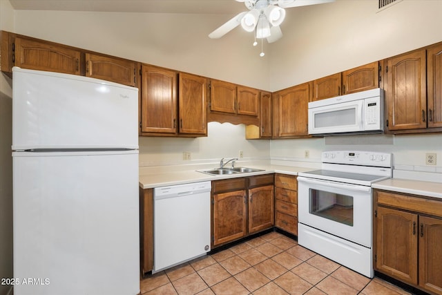 kitchen with brown cabinetry, white appliances, light countertops, and a sink