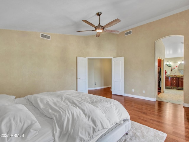 19506 N 73rd Ave, Glendale, AZ 85308 - bedroom with arched walkways, wood finished floors, baseboards, connected bathroom, and a ceiling fan