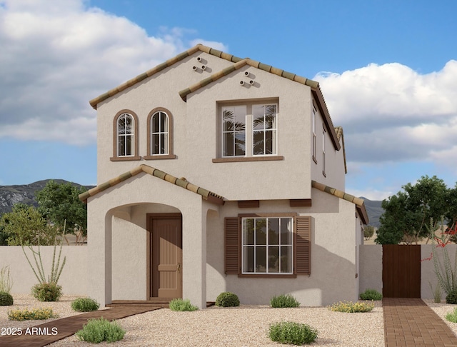 mediterranean / spanish house with a tiled roof, fence, a mountain view, and stucco siding