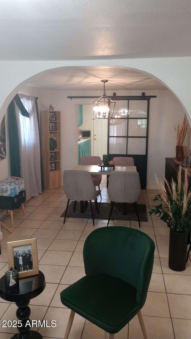 735 E 3rd St, Douglas, AZ 85608 - dining space with light tile patterned floors, arched walkways, and a textured ceiling