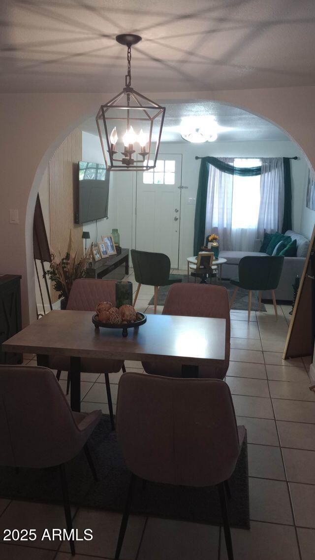 735 E 3rd St, Douglas, AZ 85608 - dining space featuring arched walkways, light tile patterned floors, and a chandelier