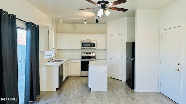 kitchen featuring stainless steel appliances, light wood finished floors, a sink, and white cabinets