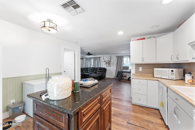3508 E Gelding Dr, Phoenix, AZ 85032 - kitchen with white microwave, light wood-style flooring, a wainscoted wall, white cabinetry, and open floor plan