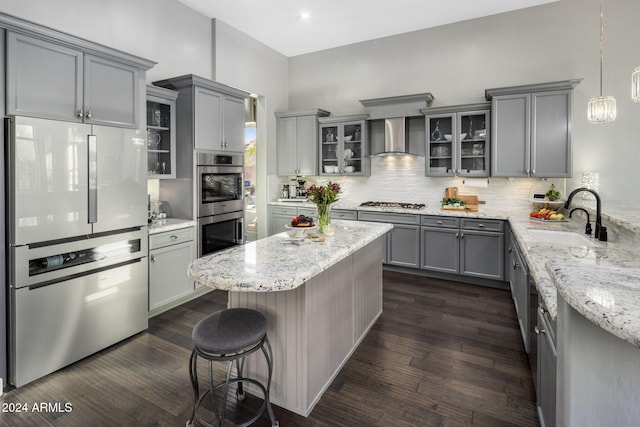 kitchen featuring wall chimney range hood, dark hardwood / wood-style floors, gray cabinets, hanging light fixtures, and sink