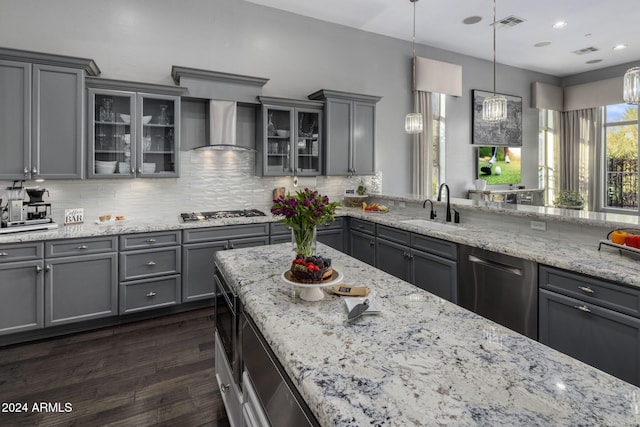 kitchen with sink, dark hardwood / wood-style floors, gray cabinets, wall chimney range hood, and pendant lighting