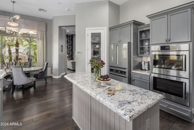 kitchen with dark wood-type flooring, gray cabinetry, a kitchen island, and stainless steel appliances