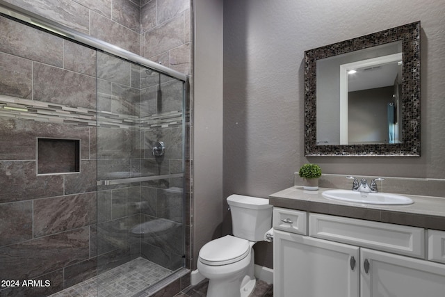 bathroom with vanity, toilet, and a shower with shower door