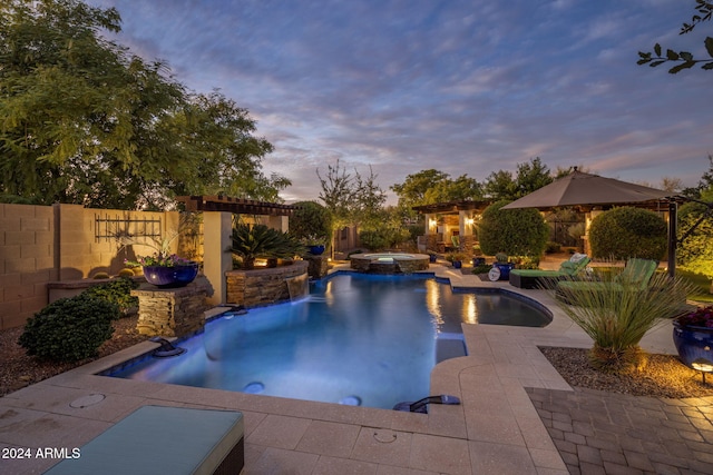 pool at dusk featuring pool water feature, an in ground hot tub, and a patio area