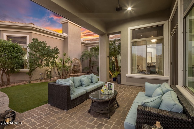 patio terrace at dusk with ceiling fan, a yard, and an outdoor hangout area