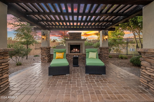 patio terrace at dusk featuring an outdoor stone fireplace and a pergola