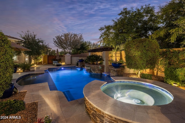 pool at dusk with pool water feature, an in ground hot tub, and a patio area